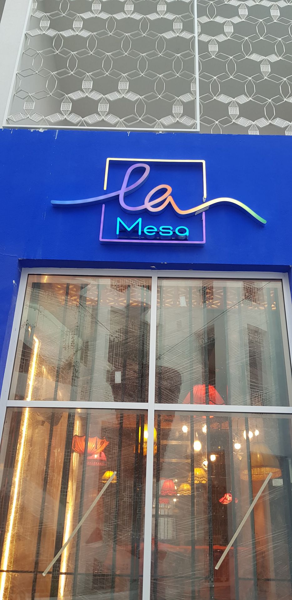 Colorful illuminated storefront sign on Le Mesa facade