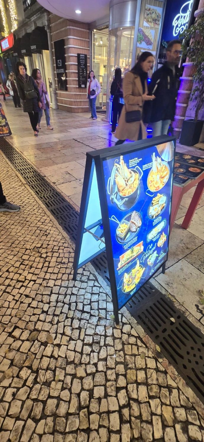 Double-sided illuminated A-board for restaurant promotion in outdoor setting